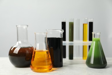 Photo of Laboratory glassware with different types of oil on white table