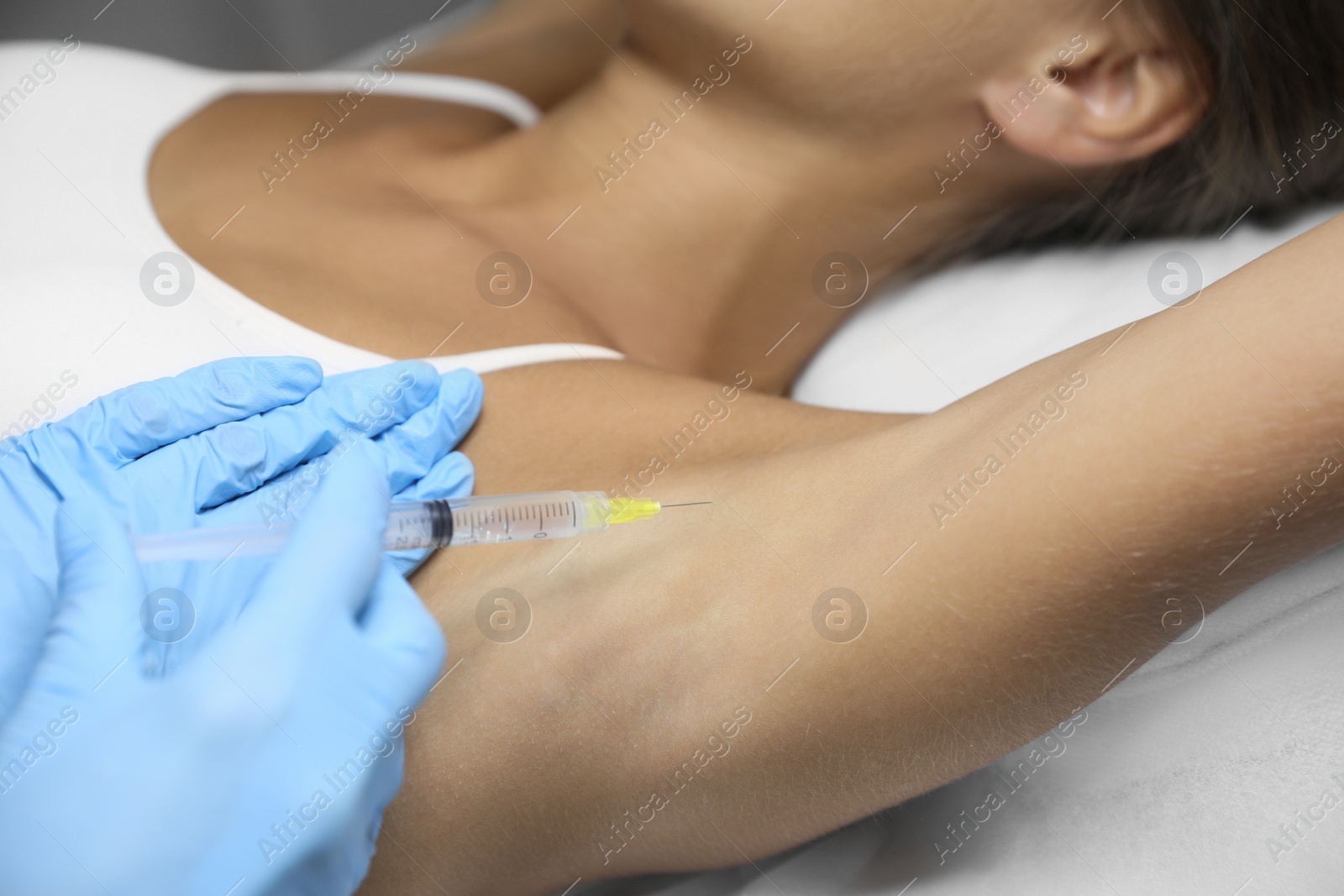Photo of Young woman getting armpits injection in salon, closeup