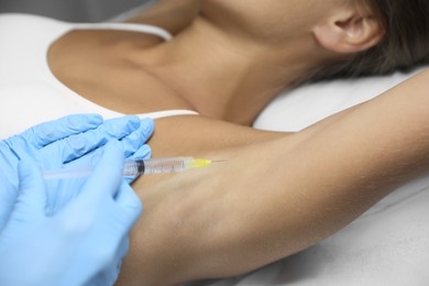 Photo of Young woman getting armpits injection in salon, closeup