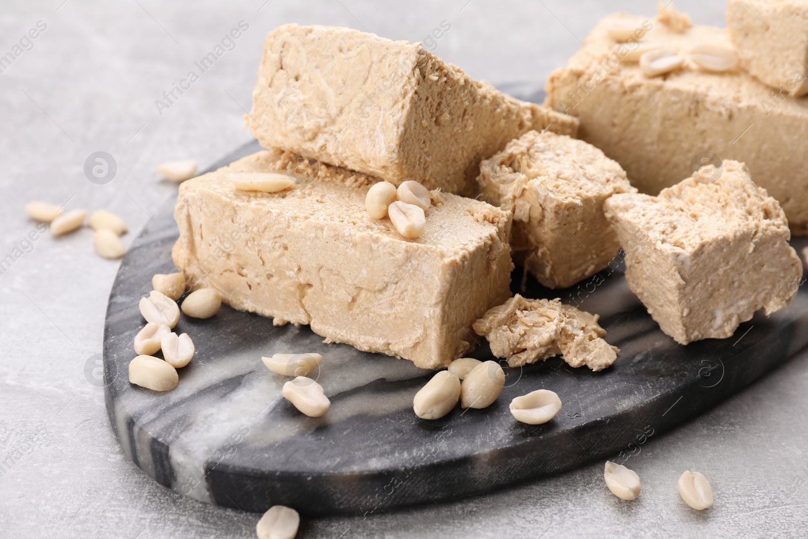 Photo of Pieces of tasty halva on light gray table, closeup