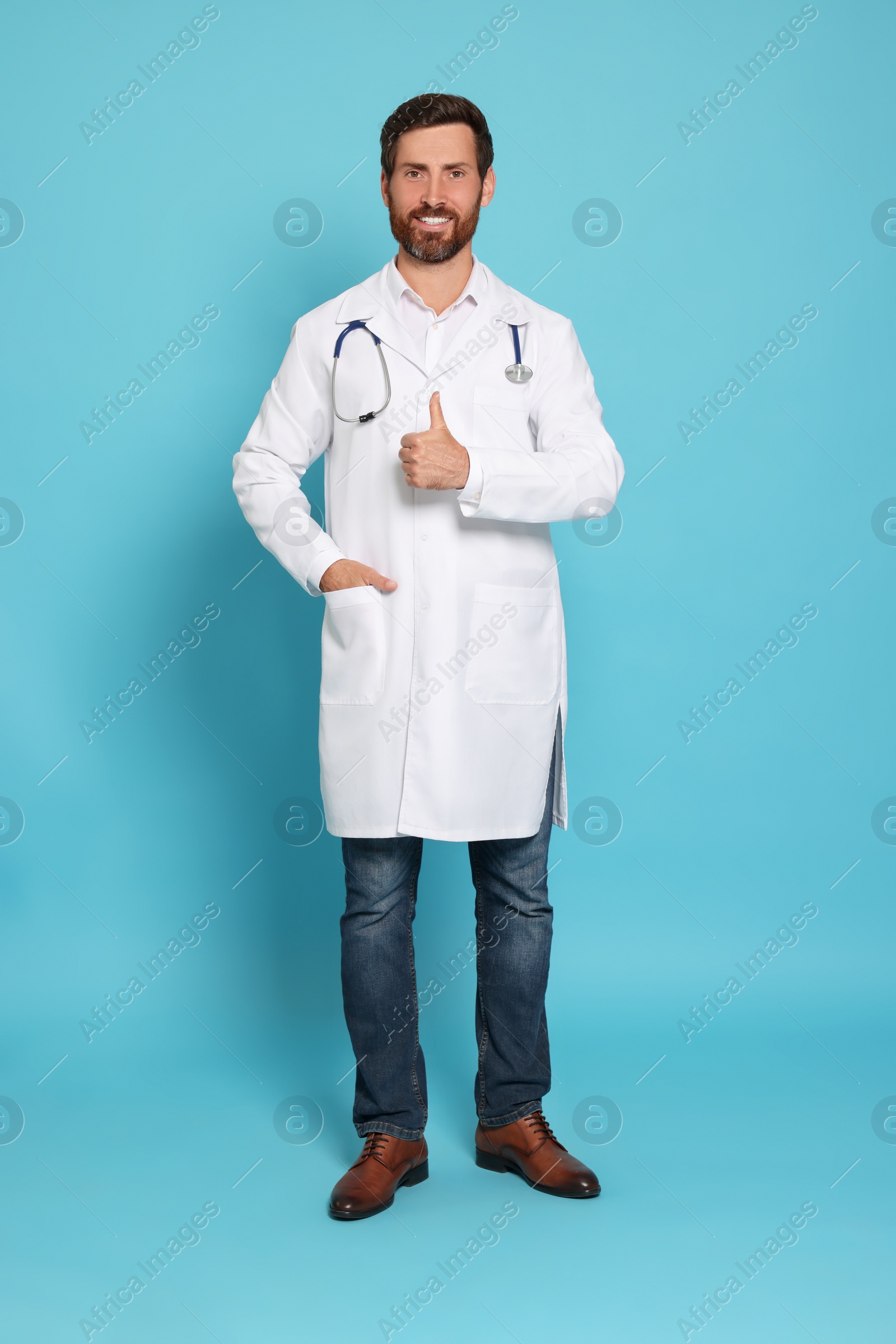 Photo of Full length portrait of doctor with stethoscope on light blue background