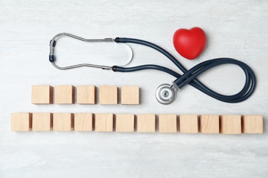 Photo of Wooden cubes with text Heart Palpitations and stethoscope on light background, flat lay