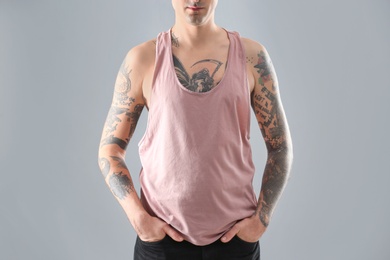 Young man with stylish tattoos on grey background