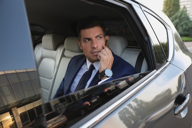 Photo of Handsome man talking on phone in modern car