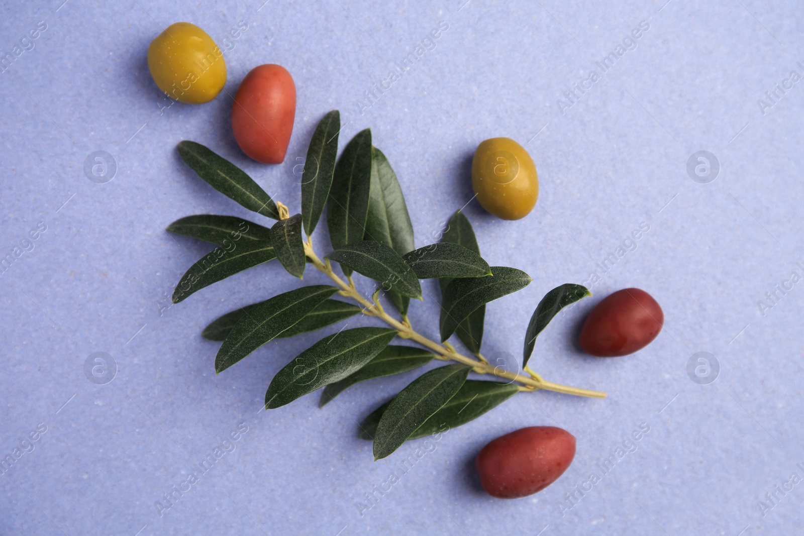 Photo of Different fresh olives and leaves on violet background, flat lay