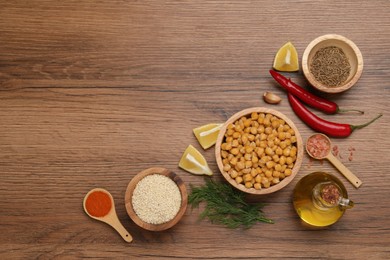 Delicious chickpeas and different products on wooden table, flat lay with space for text. Hummus ingredients