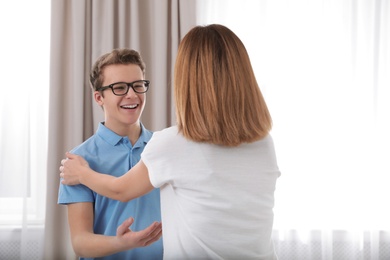 Mother hugging her teenager son at home