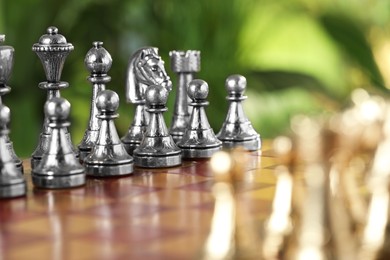 Photo of Golden and silver chess pieces on game board against blurred background, selective focus