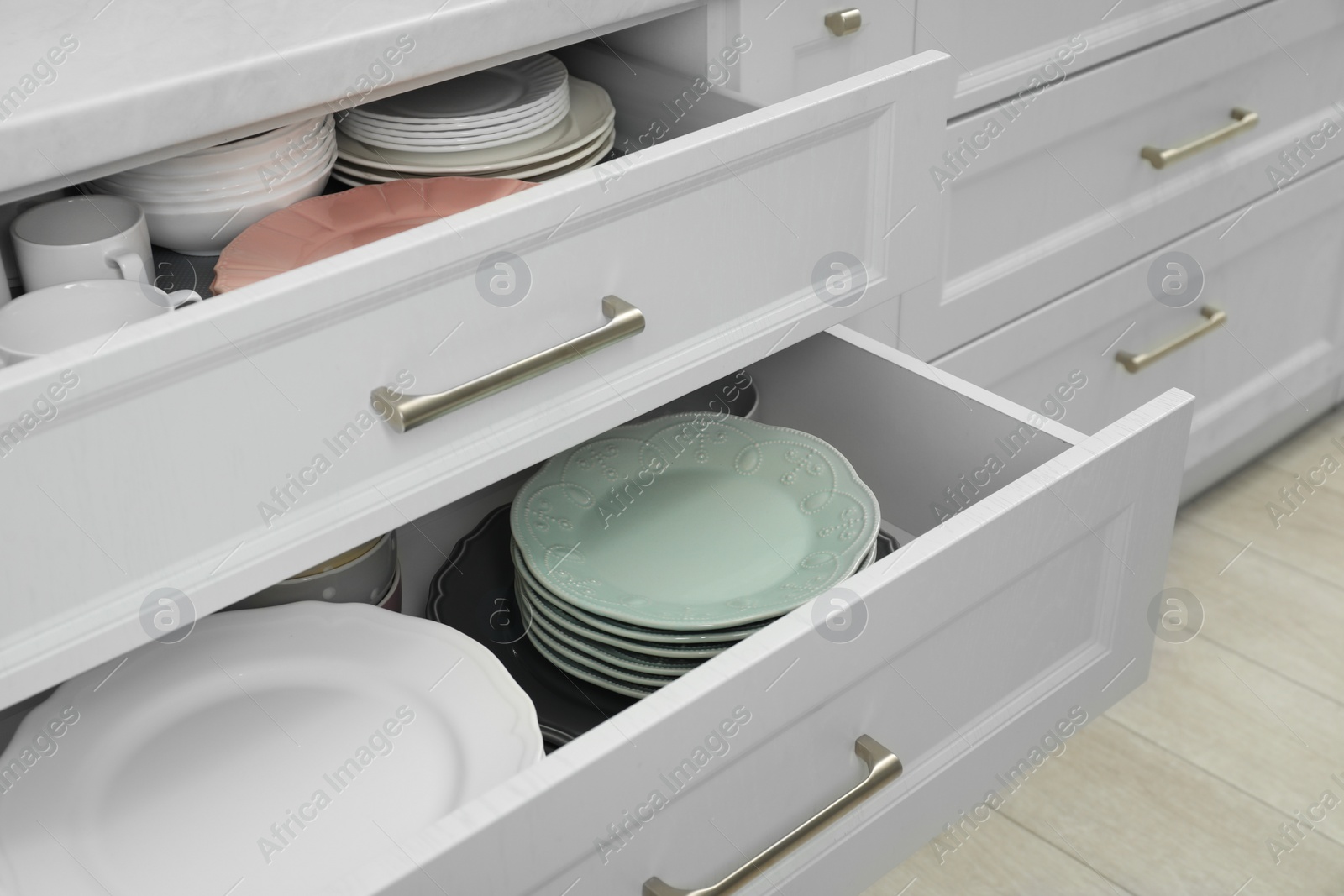 Photo of Clean plates and bowls in drawers indoors