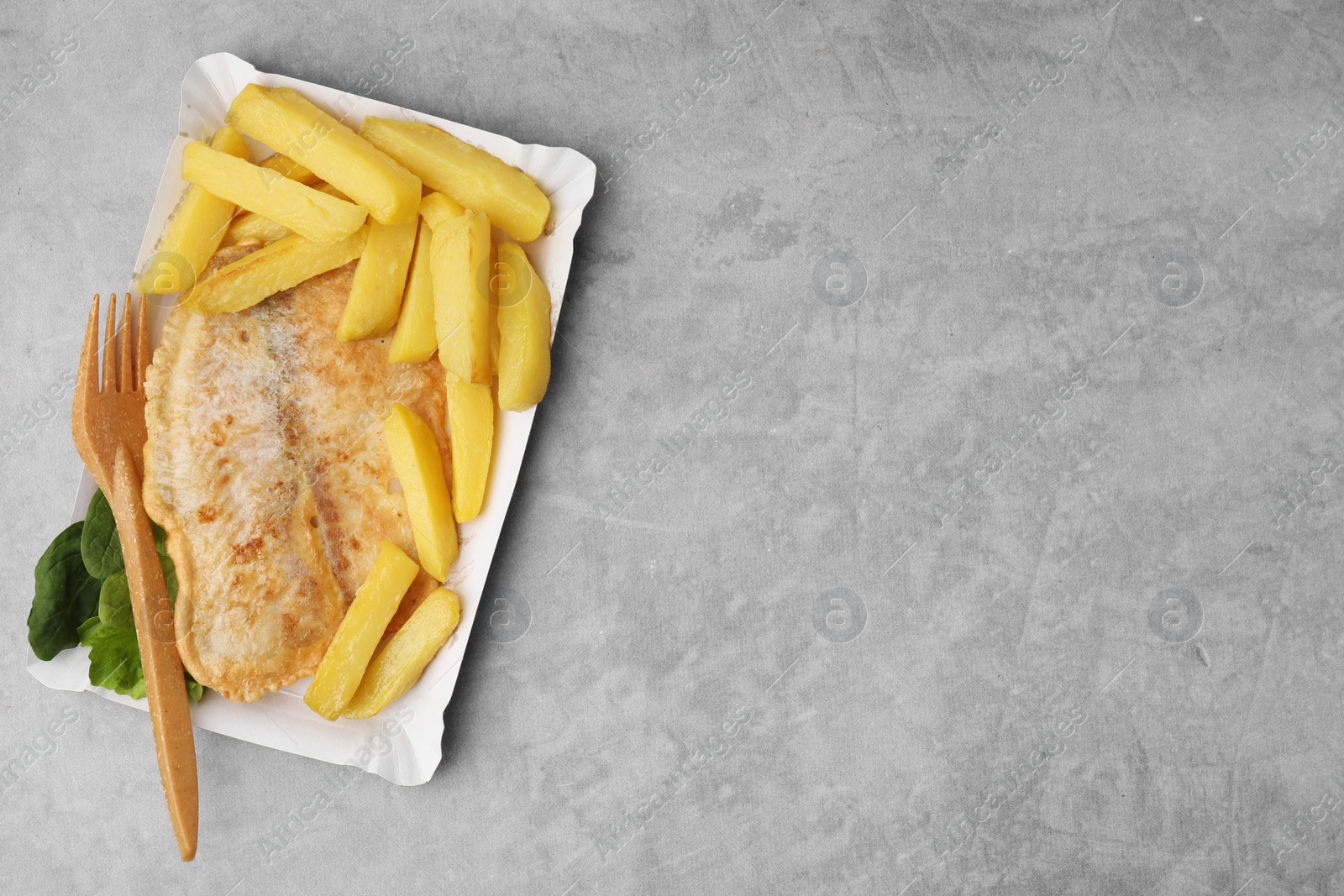Photo of Delicious fish and chips served on gray table, top view. Space for text