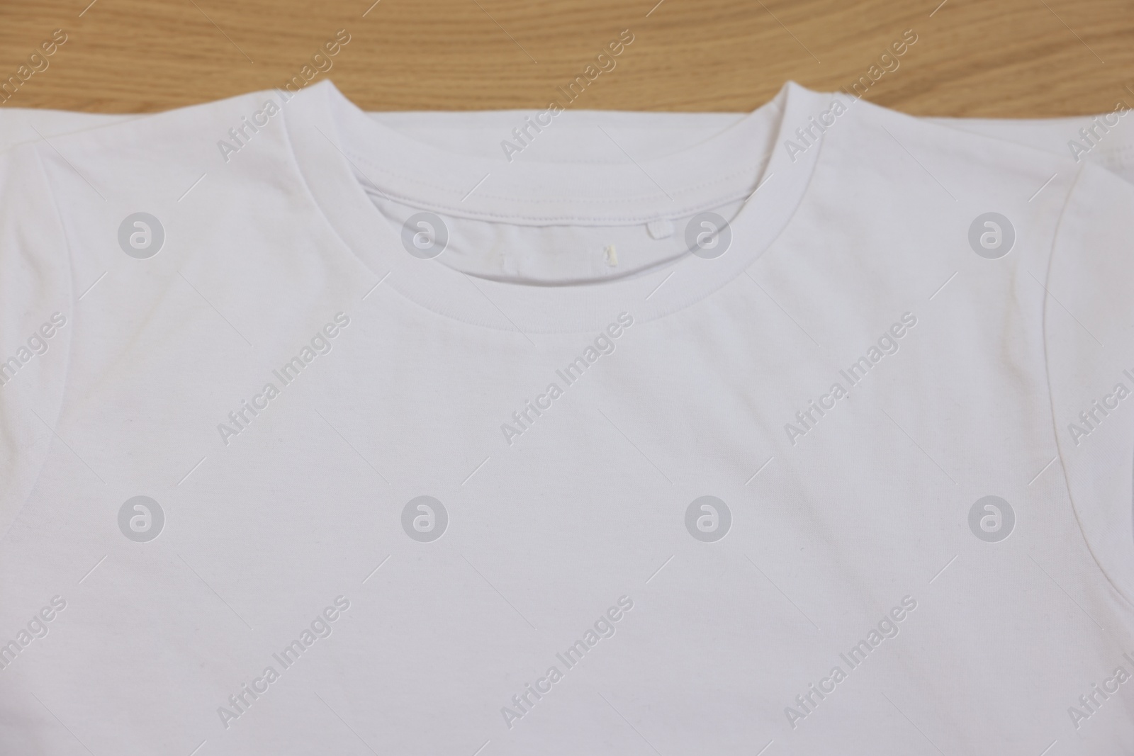 Photo of Clean white t-shirt of wooden table, top view