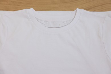 Photo of Clean white t-shirt of wooden table, top view