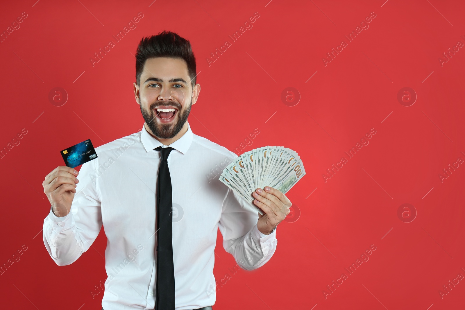 Photo of Emotional young man with money and credit card on crimson background. Space for text