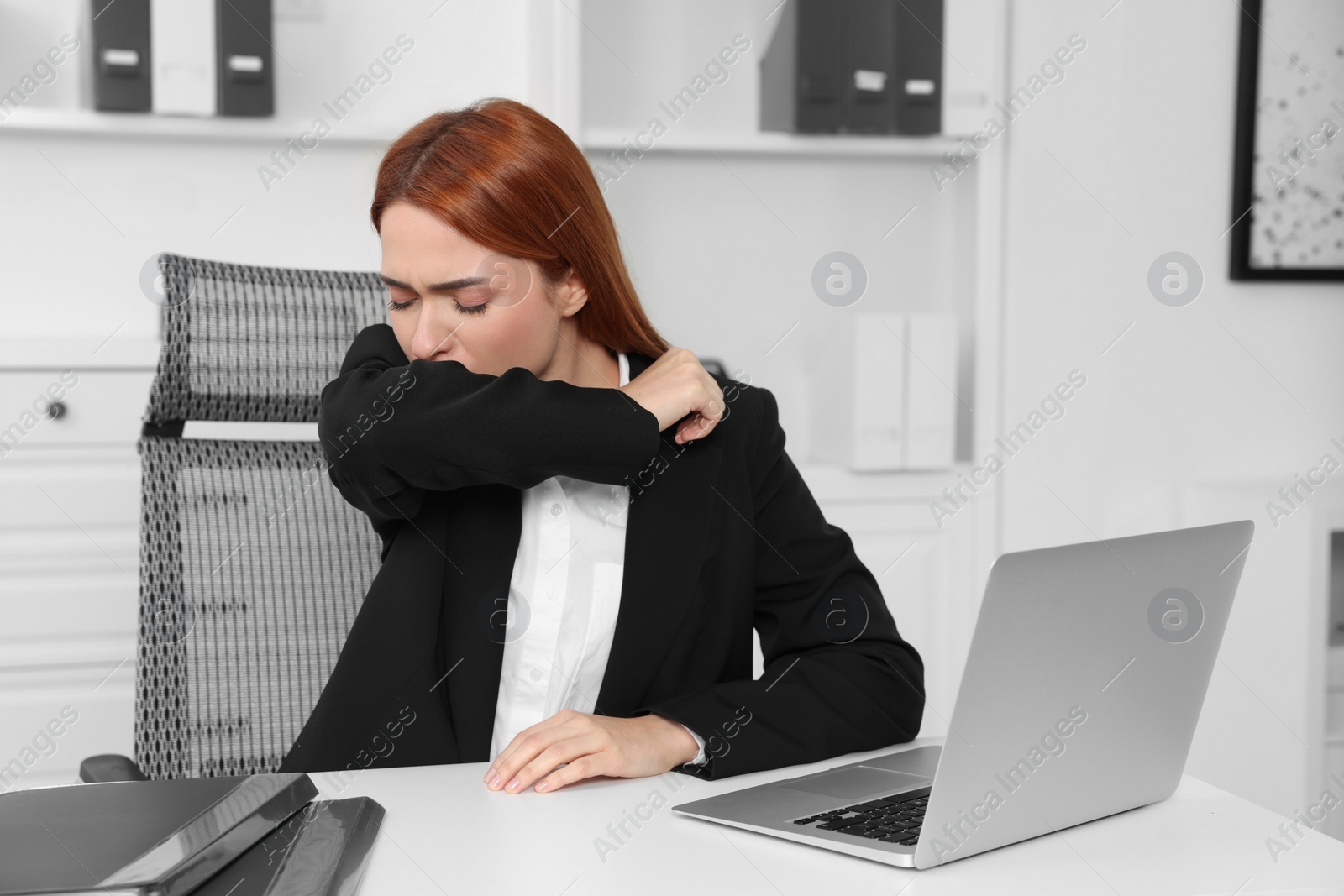 Photo of Woman coughing at table in office. Cold symptoms