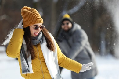 Happy couple playing snowballs on winter day outdoors