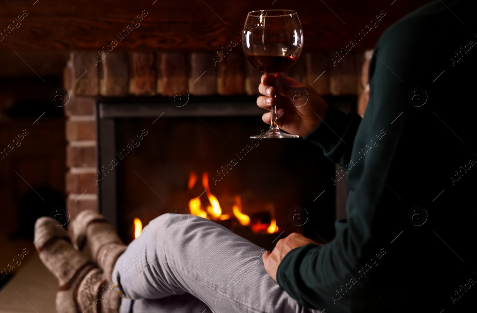 Photo of Man with glass of wine near fireplace at home, closeup