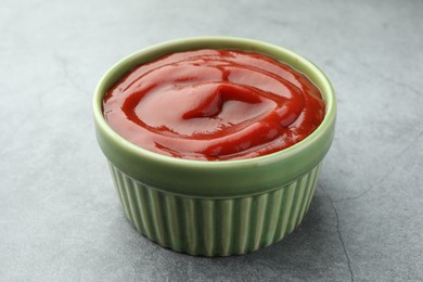 Bowl of tasty ketchup on light grey table, closeup