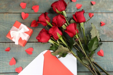 Photo of Flat lay composition with beautiful red roses and gift box on blue wooden background. Valentine's Day celebration