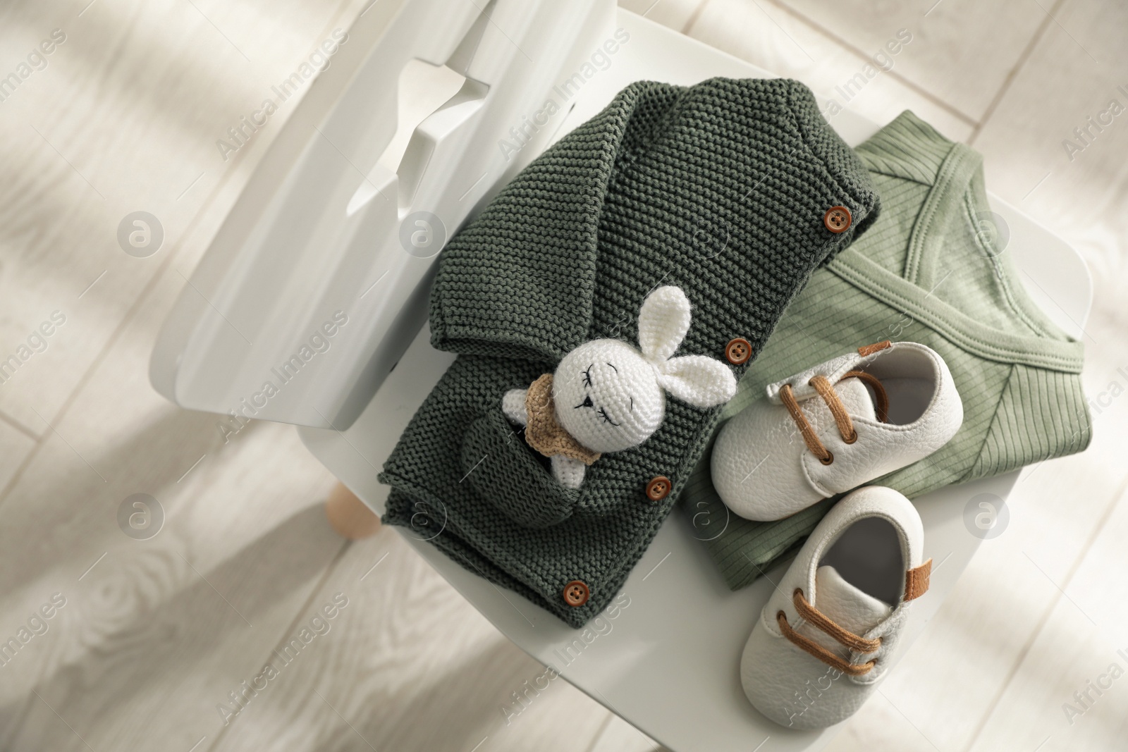 Photo of Baby clothes, shoes and toy on chair indoors, top view