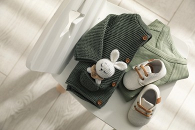 Photo of Baby clothes, shoes and toy on chair indoors, top view