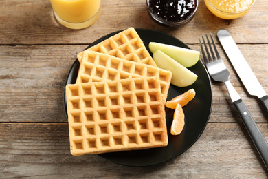 Waffles with fruits served on wooden table, above view. Delicious breakfast