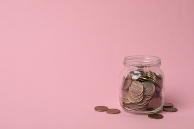 Photo of Glass jar with coins on pink background, space for text