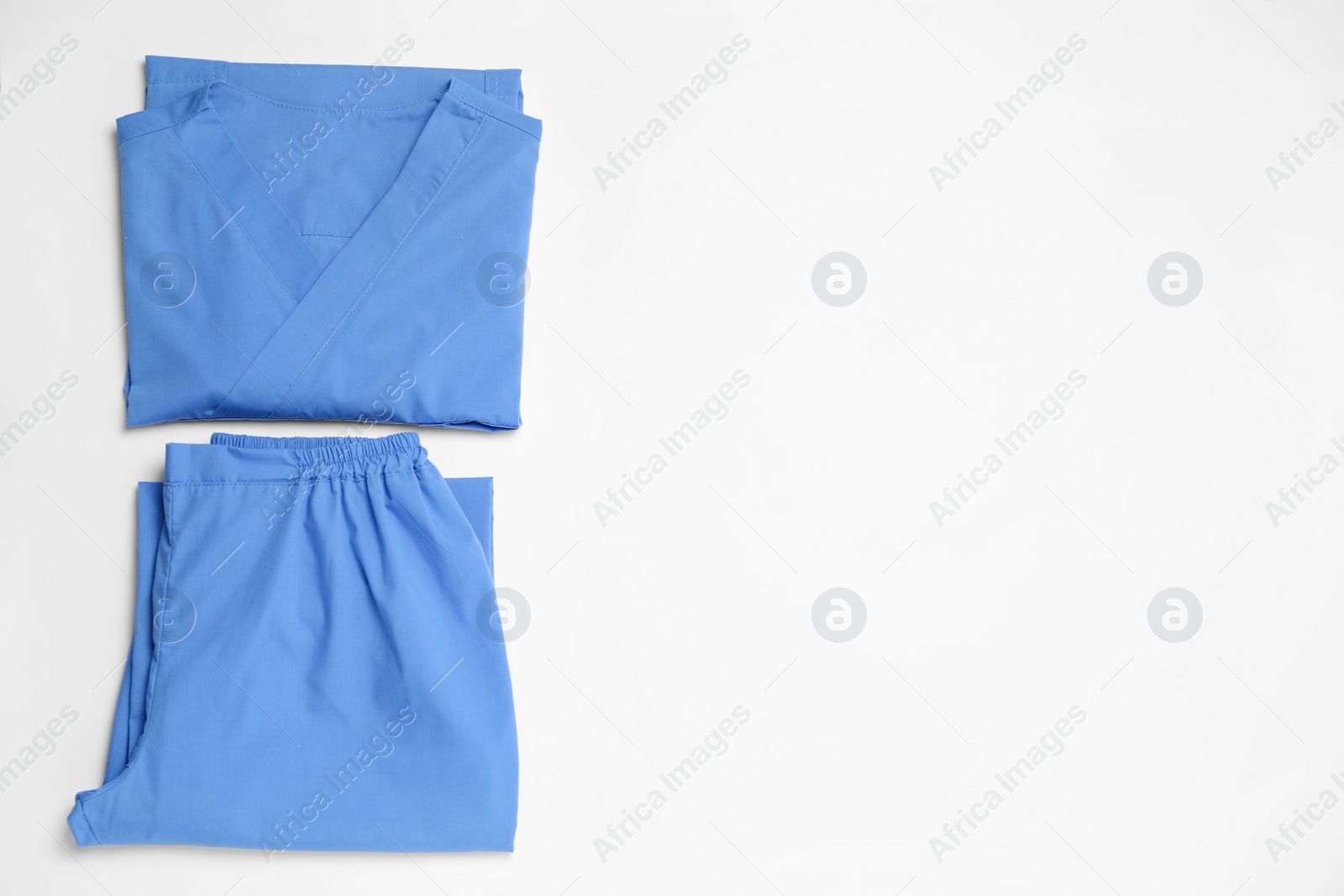 Photo of Light blue medical uniforms on white background, flat lay. Space for text