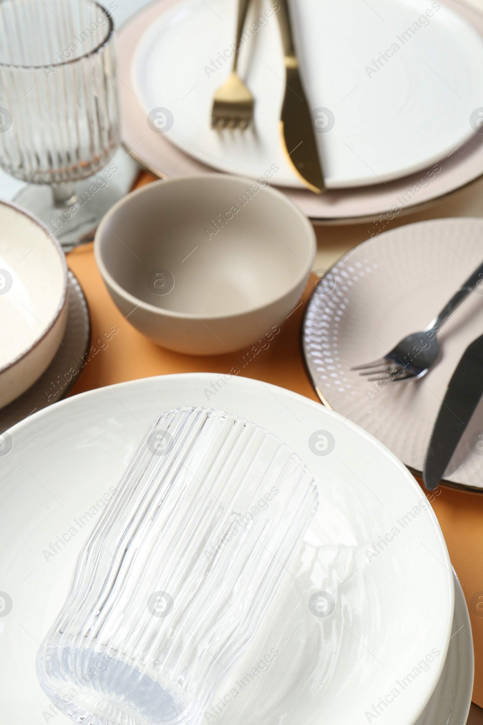 Photo of Clean plates, bowls, glass and cutlery on table