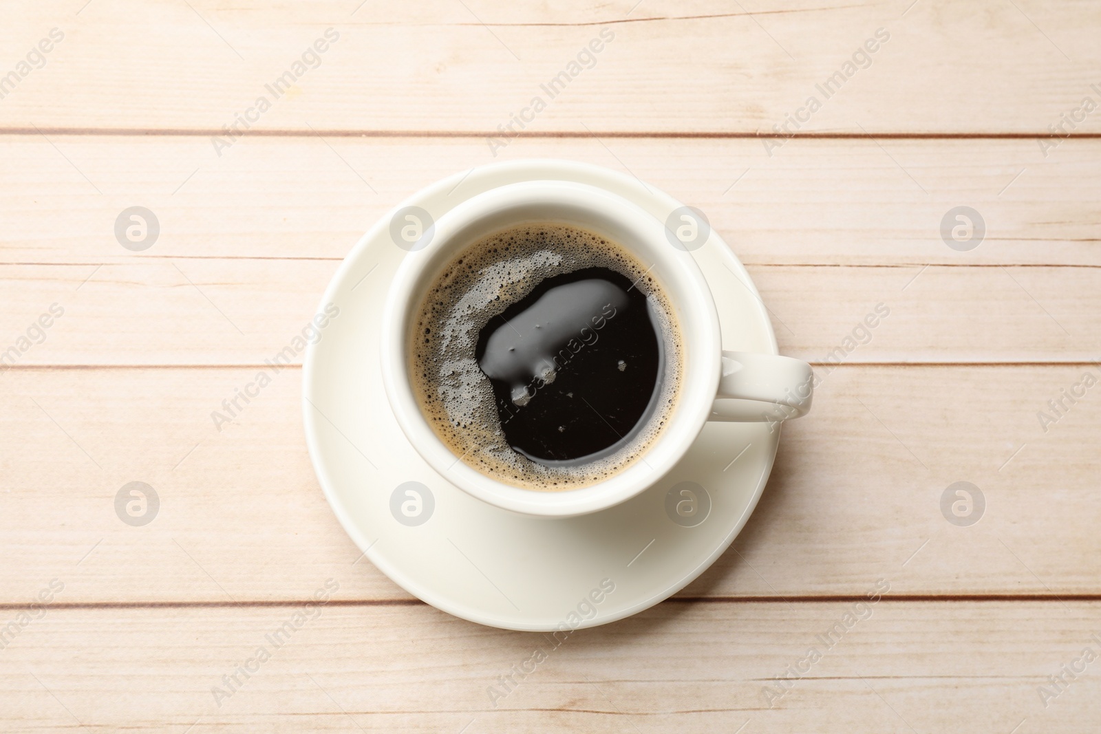 Photo of Cup of aromatic coffee on light wooden table, top view