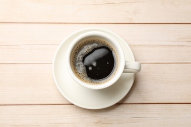 Photo of Cup of aromatic coffee on light wooden table, top view