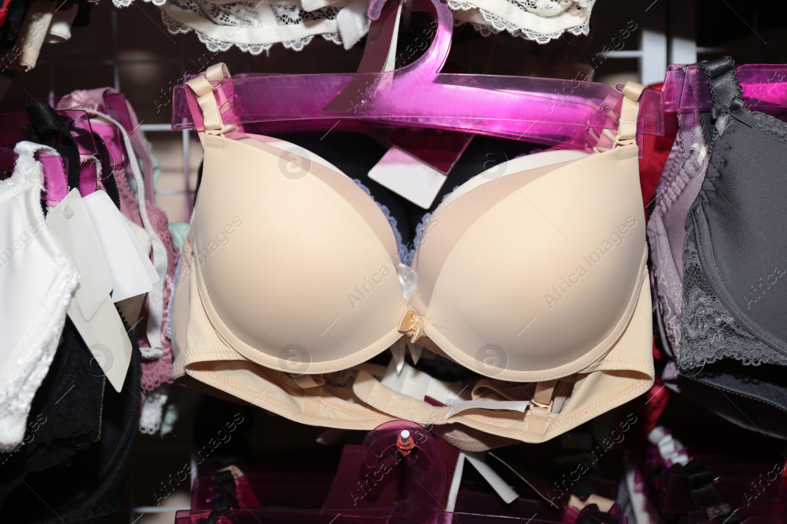 Photo of Beige beautiful bra on hanger in underwear store