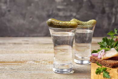 Photo of Cold Russian vodka with snacks on wooden table, closeup