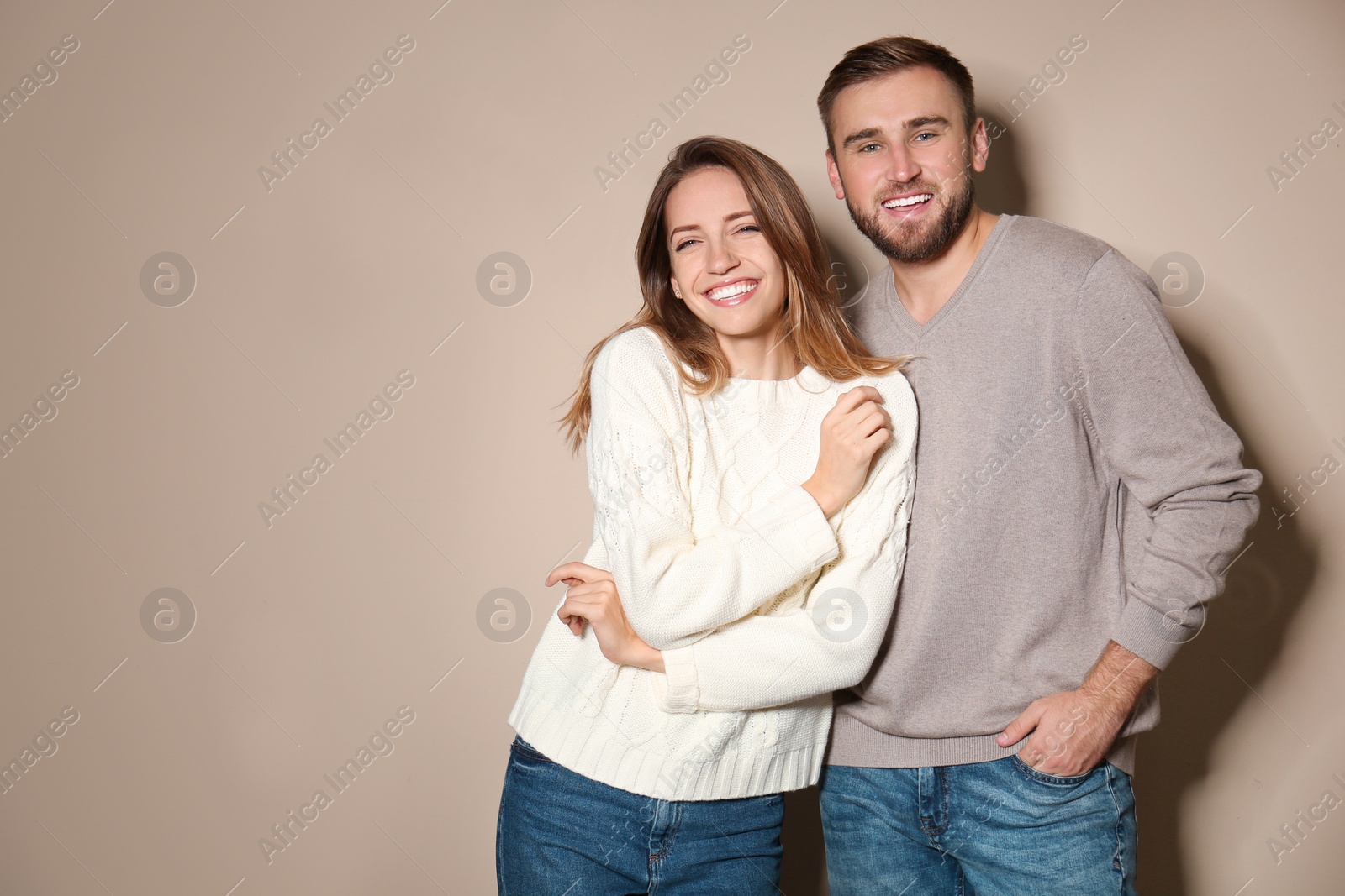 Image of Lovely couple in warm sweaters on beige background. Space for text