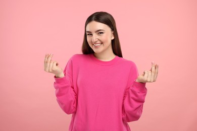 Photo of Happy woman showing money gesture on pink background