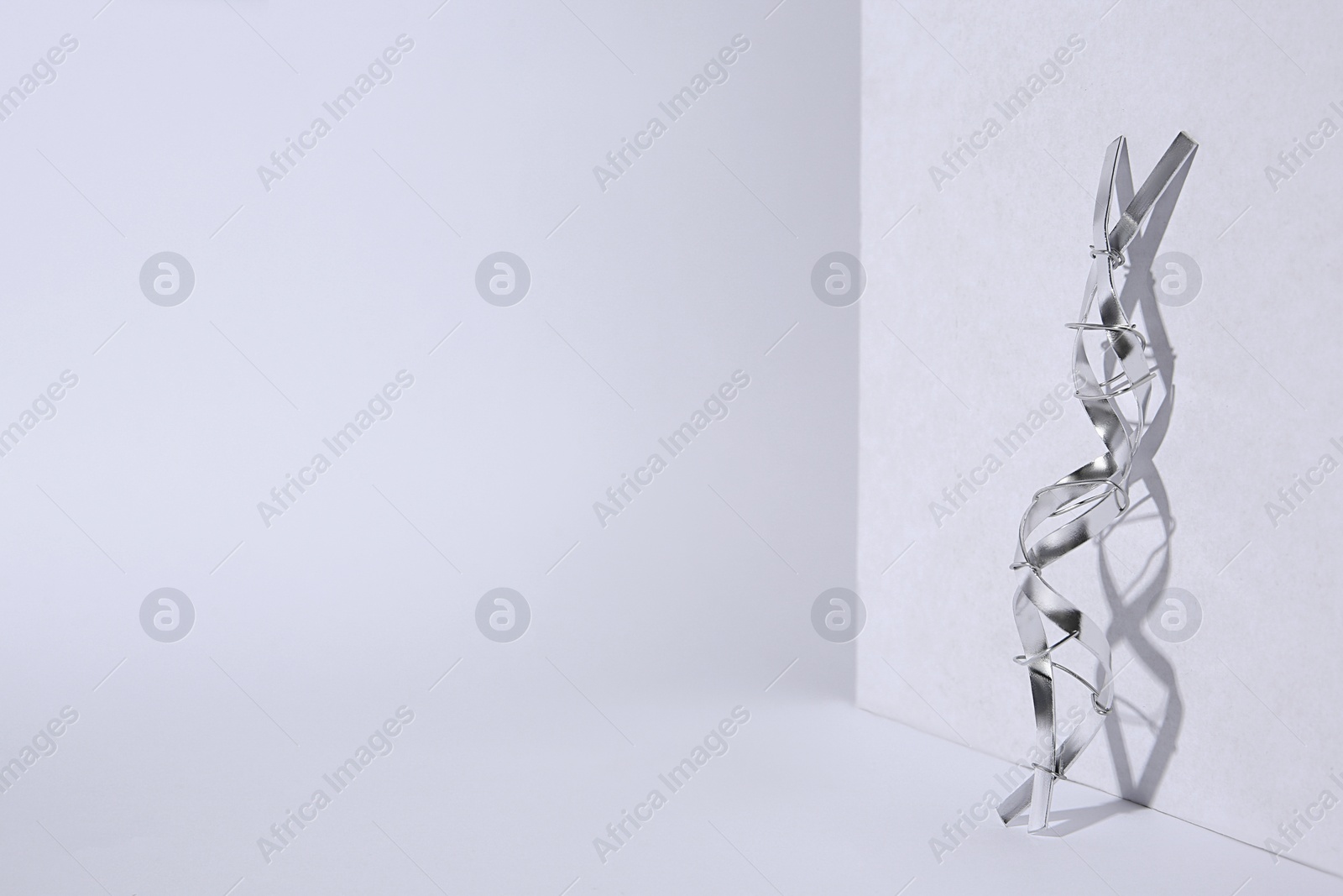 Photo of DNA molecular chain model made of metal on white background, space for text