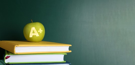 Image of Apple with carved letter A and plus symbol as school grade on books near green chalkboard. Banner design with space for text