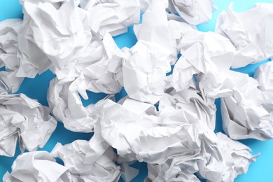 Crumpled sheets of paper on light blue background, closeup