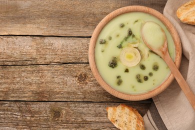 Photo of Delicious leek soup served on wooden table, flat lay. Space for text
