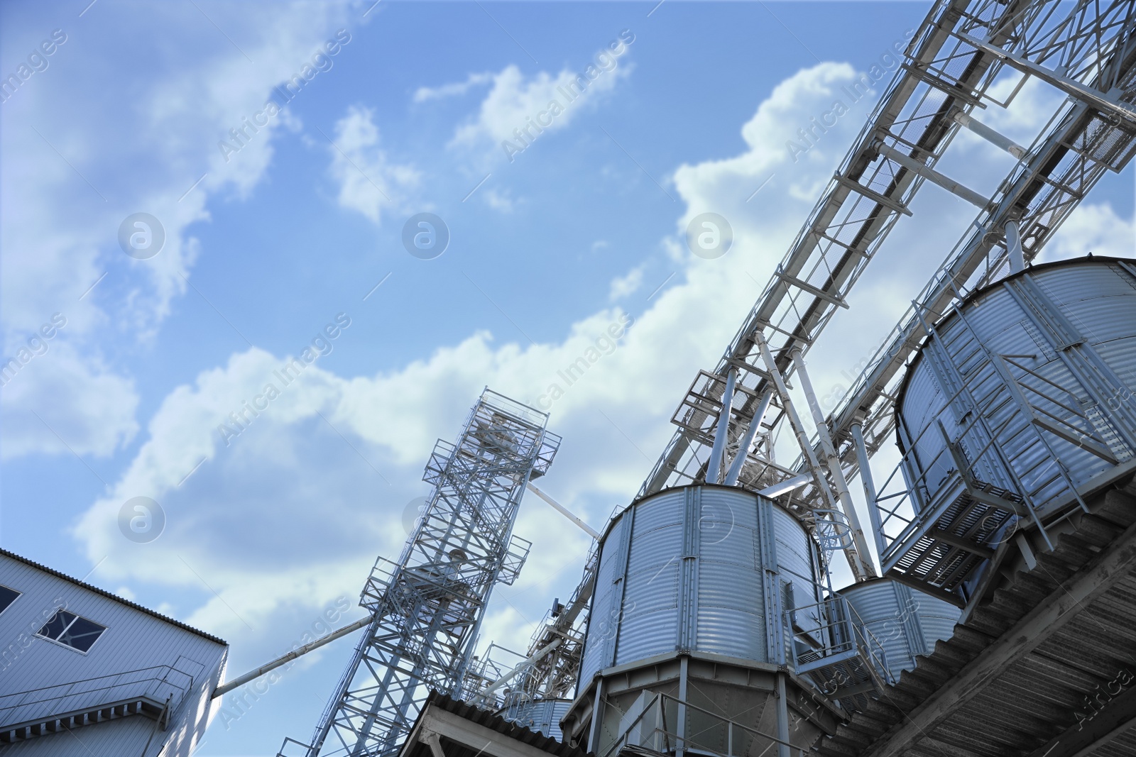 Photo of Modern granaries for storing cereal grains against blue sky, low angle view