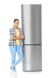 Young woman near closed refrigerator on white background