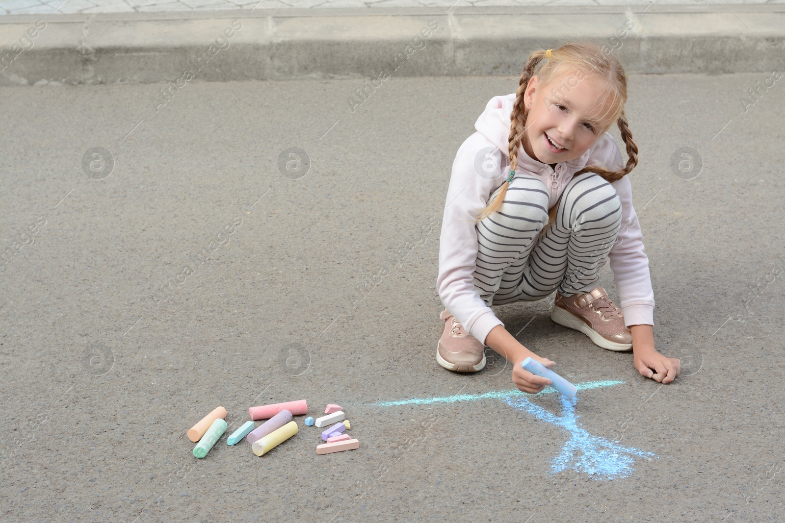 Photo of Little child drawing happy family with chalk on asphalt