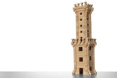 Photo of Wooden tower on light grey table against white background, space for text. Children's toy