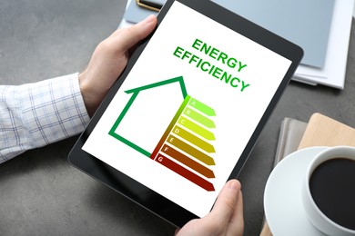 Image of Energy efficiency. Man using tablet with colorful rating on display at table, closeup