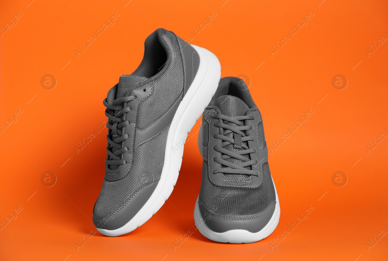 Photo of Pair of stylish sport shoes on orange background