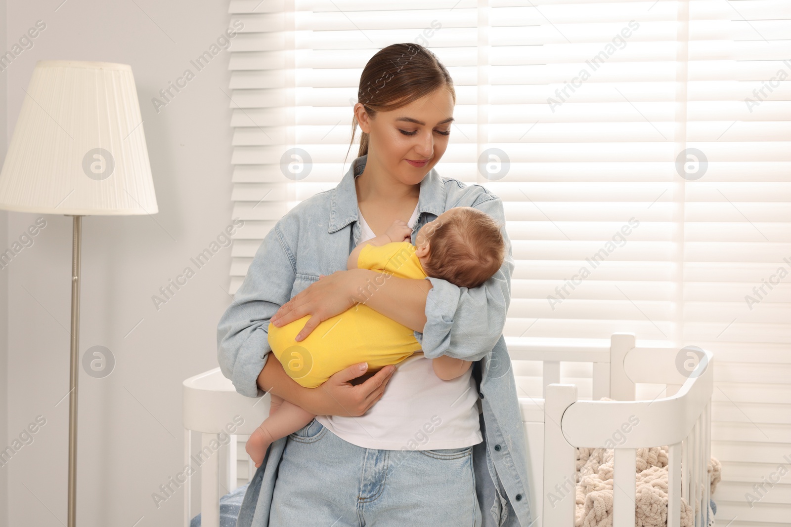 Photo of Mother holding her sleeping newborn baby in child's room