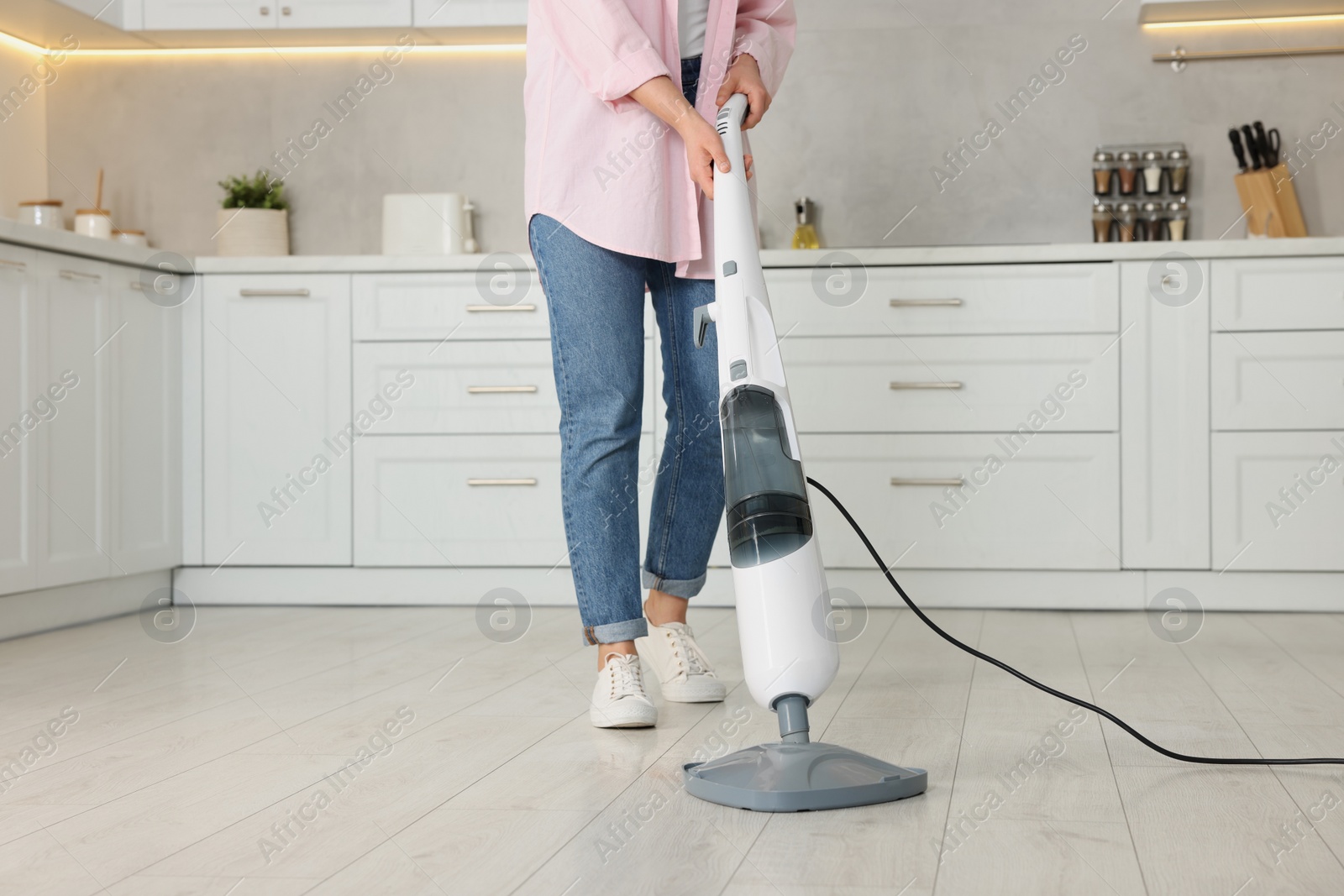 Photo of Woman cleaning floor with steam mop in kitchen at home, closeup