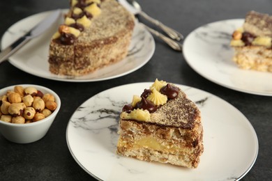 Photo of Delicious Kyiv Cake decorated with cream and hazelnuts served on black table, closeup