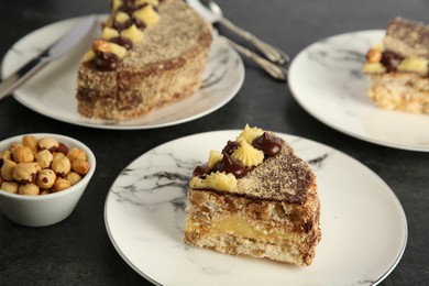 Delicious Kyiv Cake decorated with cream and hazelnuts served on black table, closeup