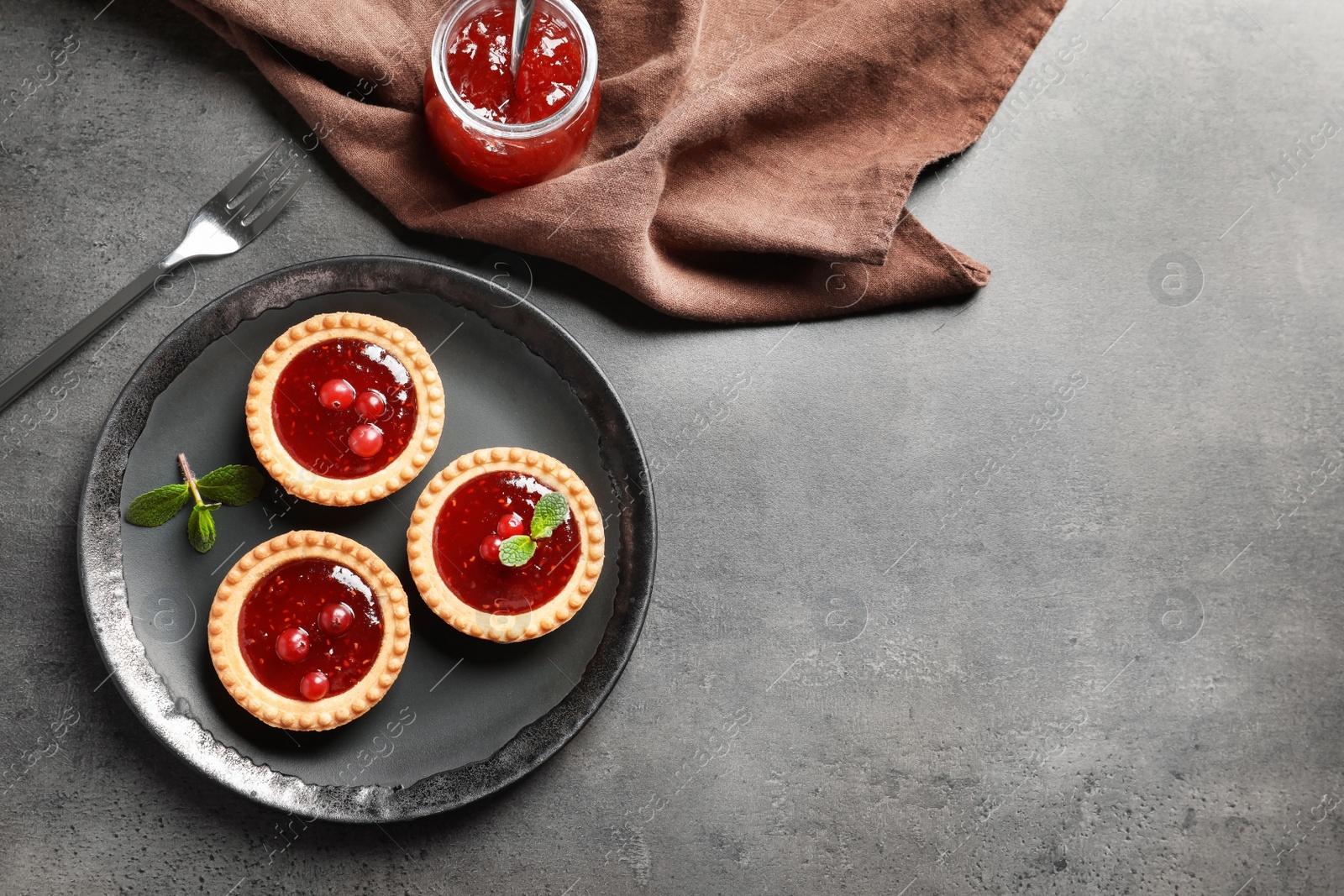 Photo of Tasty tartlets with jam on grey background