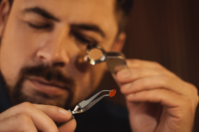 Photo of Jeweler working with gemstone on blurred background, closeup